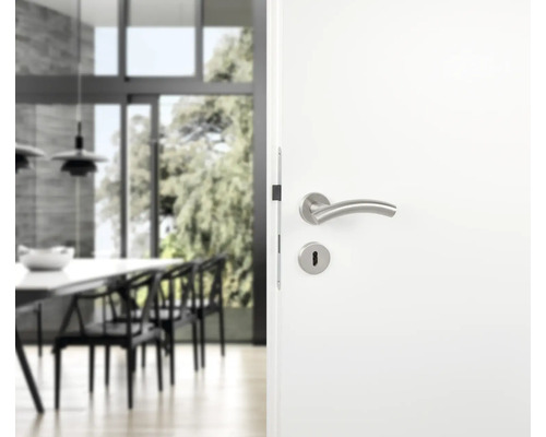 Porte blanche avec garniture de poignée de porte en acier inoxydable devant un espace de vie lumineux
