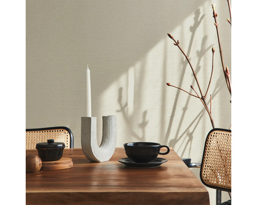 Mur beige avec décoration sur une table à manger avec une bougie, une tasse à thé et un petit bol