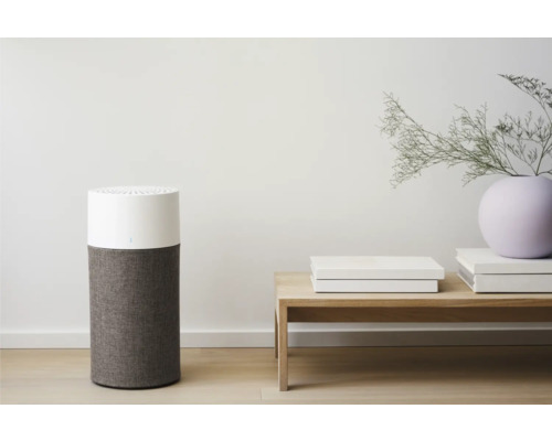 Luftreiniger mit Textilfilter neben Tisch mit Dekoration