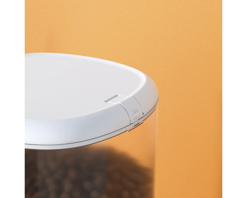 Detailansicht eines Futterautomaten mit transparentem Behälter und weißem Deckel