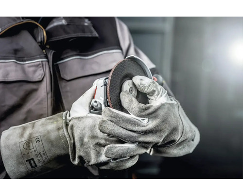 Eine Person hält eine Flex mit Schleifscheibe in Schutzhandschuhen.