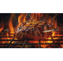 Un steak est cuit sur un grill avec un thermomètre pour barbecue