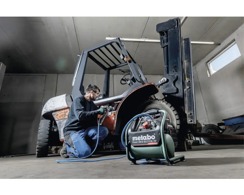 Un homme travaille avec un compresseur Metabo sur un chariot élévateur dans un atelier.
