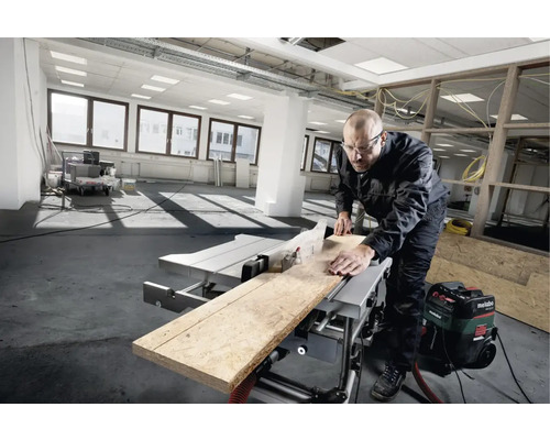 Handwerker bei der Arbeit mit einer Tischkreissäge in einem hellen Raum