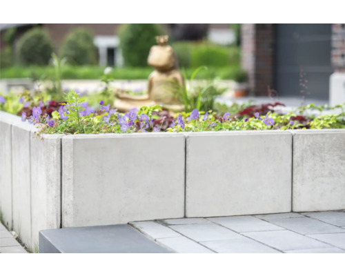 Jardinière surélevée en blocs de béton plantée de fleurs dans le jardin.