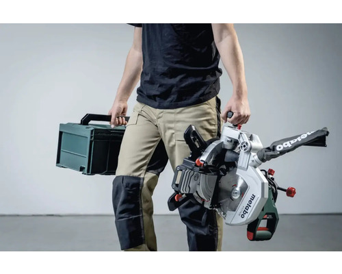Eine Person trägt eine Metabo Kappsäge und einen Werkzeugkoffer.