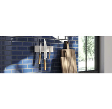 Küchenszene mit blauen Fliesen, magnetischem Messerhalter mit Messern und Holzschneidebrettern