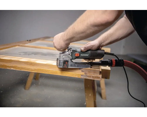 Un homme travaille sur un cadre en bois avec une fraise à rainurer Metabo.