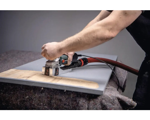 Une personne utilise une fraise à rainurer les murs sur une pièce.