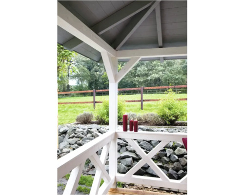 Vue depuis une véranda en bois blanc sur un jardin avec des pierres, des plantes et une clôture en bois