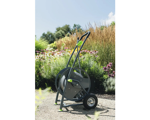 Gartenschlauchwagen mit Rädern und Gartenschlauch vor Blumenbeet