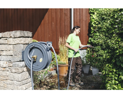 Frau giesst Pflanzen mit einer Schlauchtrommel von Geka im Garten