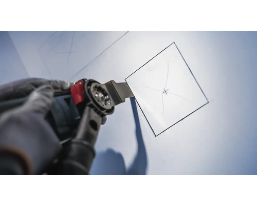 Outil multifonction oscillant coupant une ouverture carrée dans un mur.