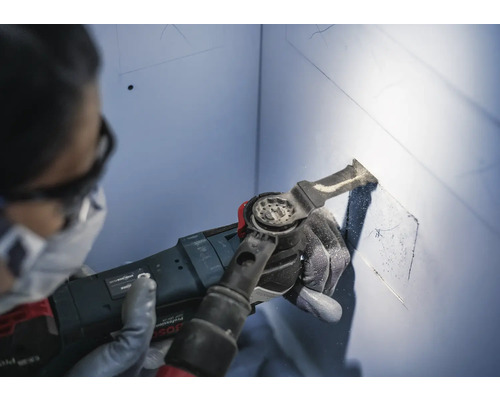 Une personne utilise un outil multifonction pour découper une cavité dans un mur.