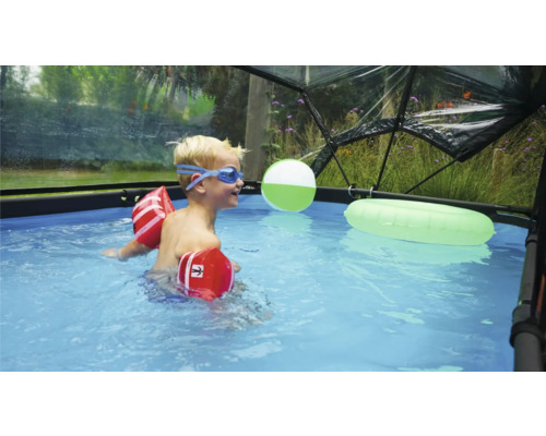 Enfant avec des brassards et des lunettes de natation dans une piscine sous un dôme de piscine
