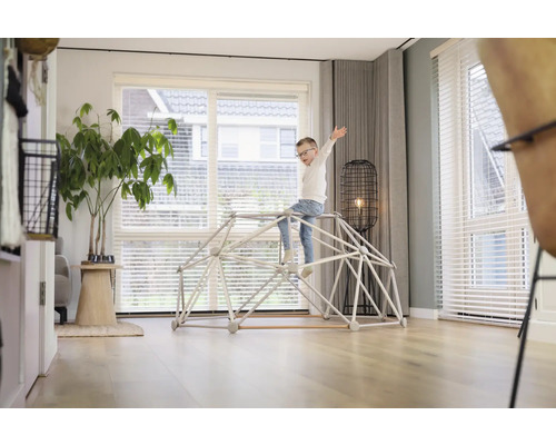 Kind spielt auf einem Klettergerüst im Wohnzimmer.