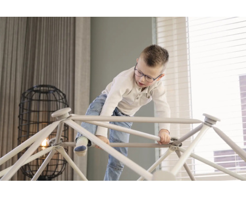 Junge klettert auf Indoor-Klettergerüst im Wohnzimmer
