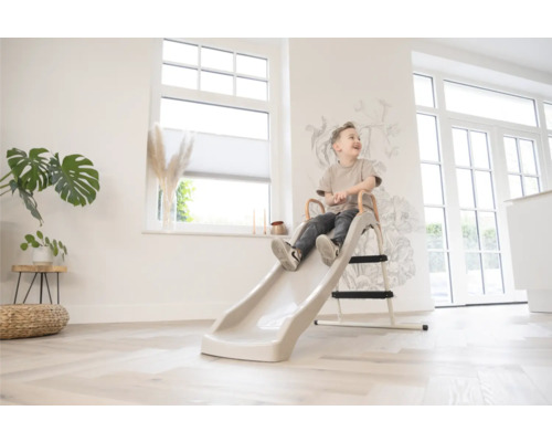 Ein Kind sitzt auf einer Rutsche in einem hellen Raum