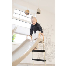 Kleinkind klettert auf eine Kinderrutsche im Innenbereich.
