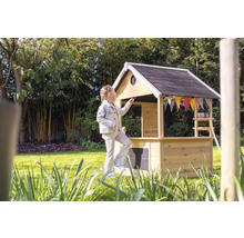 Fille devant une cabane en bois dans le jardin.
