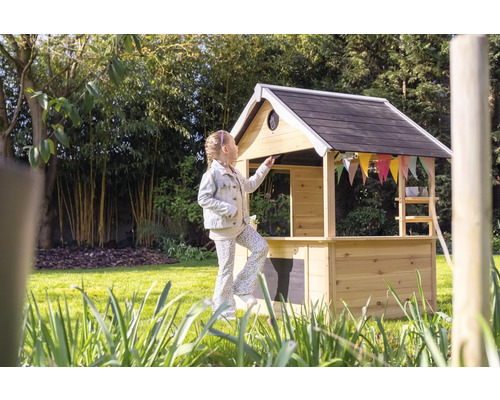 Fille devant une cabane en bois dans le jardin.