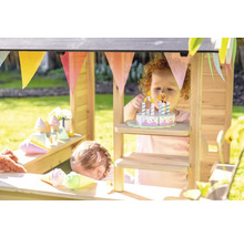 Des enfants jouent dans un magasin en bois avec des aliments jouets et une guirlande.
