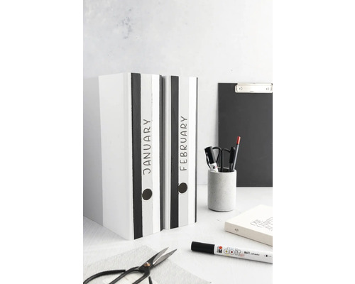 Deux classeurs portant les inscriptions janvier et février sont posés sur une table.