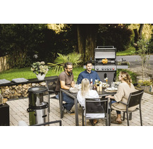 Des personnes sont assises à une table de jardin avec un gril en arrière-plan.