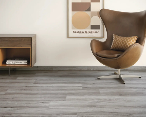 Wohnzimmer mit grauem Vinylboden, Sessel, Kommode und Wandbild