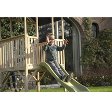 Un garçon glisse sur un toboggan de tour de jeux en bois dans le jardin.