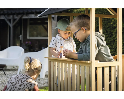 Drei Kinder spielen in einem Spielhaus aus Holz im Garten.