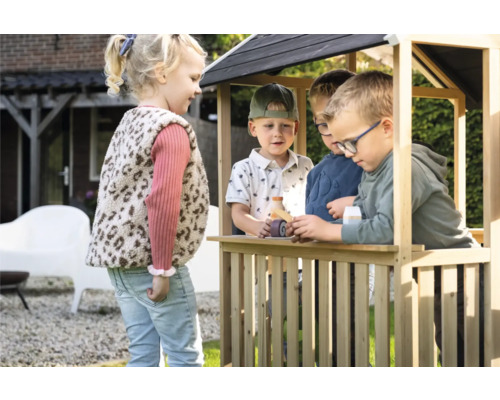 Kinder spielen in einem Holzspielhaus im Garten.