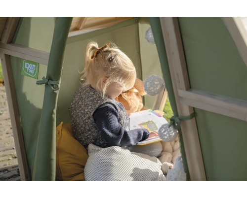 Mädchen liest Buch in Spielhaus mit Kissen und Dekoration