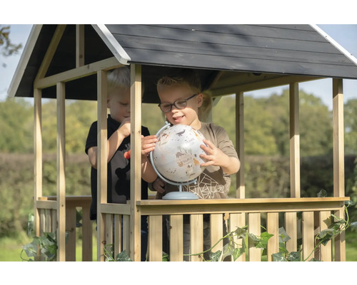 Deux enfants jouent avec un globe dans une cabane en bois dans le jardin.