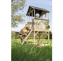 Un enfant grimpe sur une cabane de jeux en bois avec toboggan dans le jardin