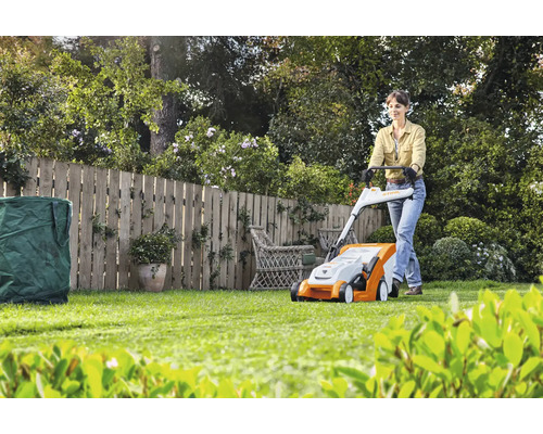 Femme utilisant une tondeuse à gazon dans le jardin