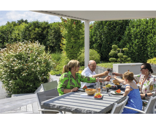 Une famille prend un repas à une table de jardin sous une pergola à l''extérieur