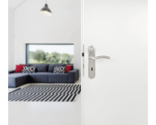 Geöffnete weiße Tür mit silbernem Türgriff in einem hellen Wohnzimmer
