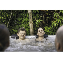 Une famille détendue profite d''un bain bouillonnant chaud dans le jardin