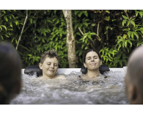 Une famille détendue profite d''un bain bouillonnant chaud dans le jardin
