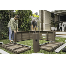 Deux personnes assemblent un abri de jardin sur une pelouse.