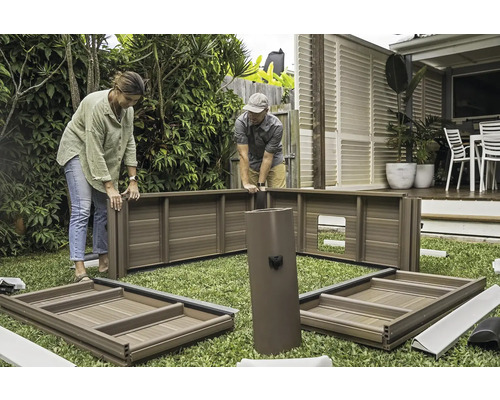 Deux personnes assemblent un abri de jardin sur une pelouse.