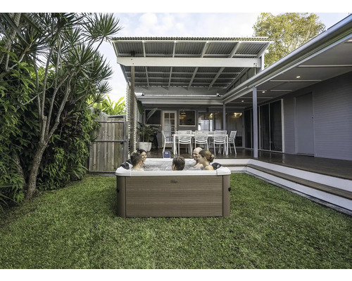 Scène avec un bain à remous dans le jardin où plusieurs personnes se détendent.