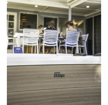 Gros plan d''un jacuzzi MSpa avec revêtement en bois et le logo MSpa. À l''arrière-plan, des personnes sont assises à une table.