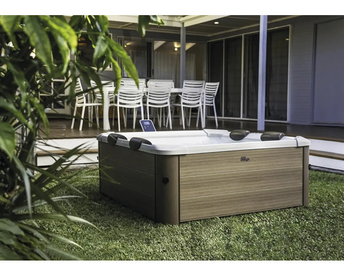 Jacuzzi d''extérieur sur pelouse devant une terrasse avec mobilier de jardin