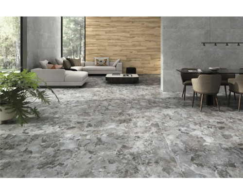 Heller Wohnraum mit Sofa, Esstisch und grau gemusterter Bodenfliese.