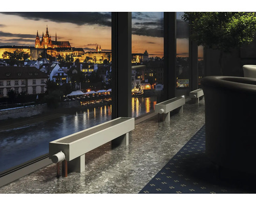 Raumansicht mit Heizkörpern vor einem Fenster mit Blick auf eine Stadt bei Nacht.