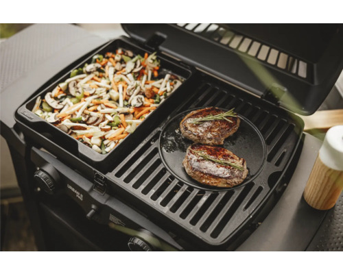 Gasgrill mit Gemüsepfanne und zwei Steaks auf dem Grillrost