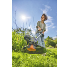 Une femme travaille avec un coupe-bordure dans le jardin.