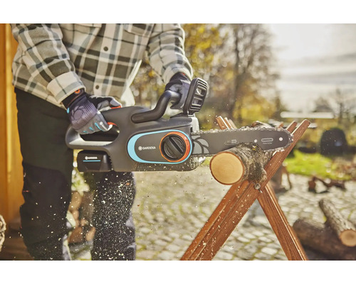 Une personne coupe du bois avec une tronçonneuse à batterie Gardena sur un chevalet de sciage en bois